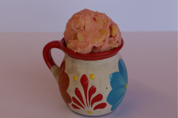 Pink guava sorbet with fruit chunks in a traditional painted clay cup