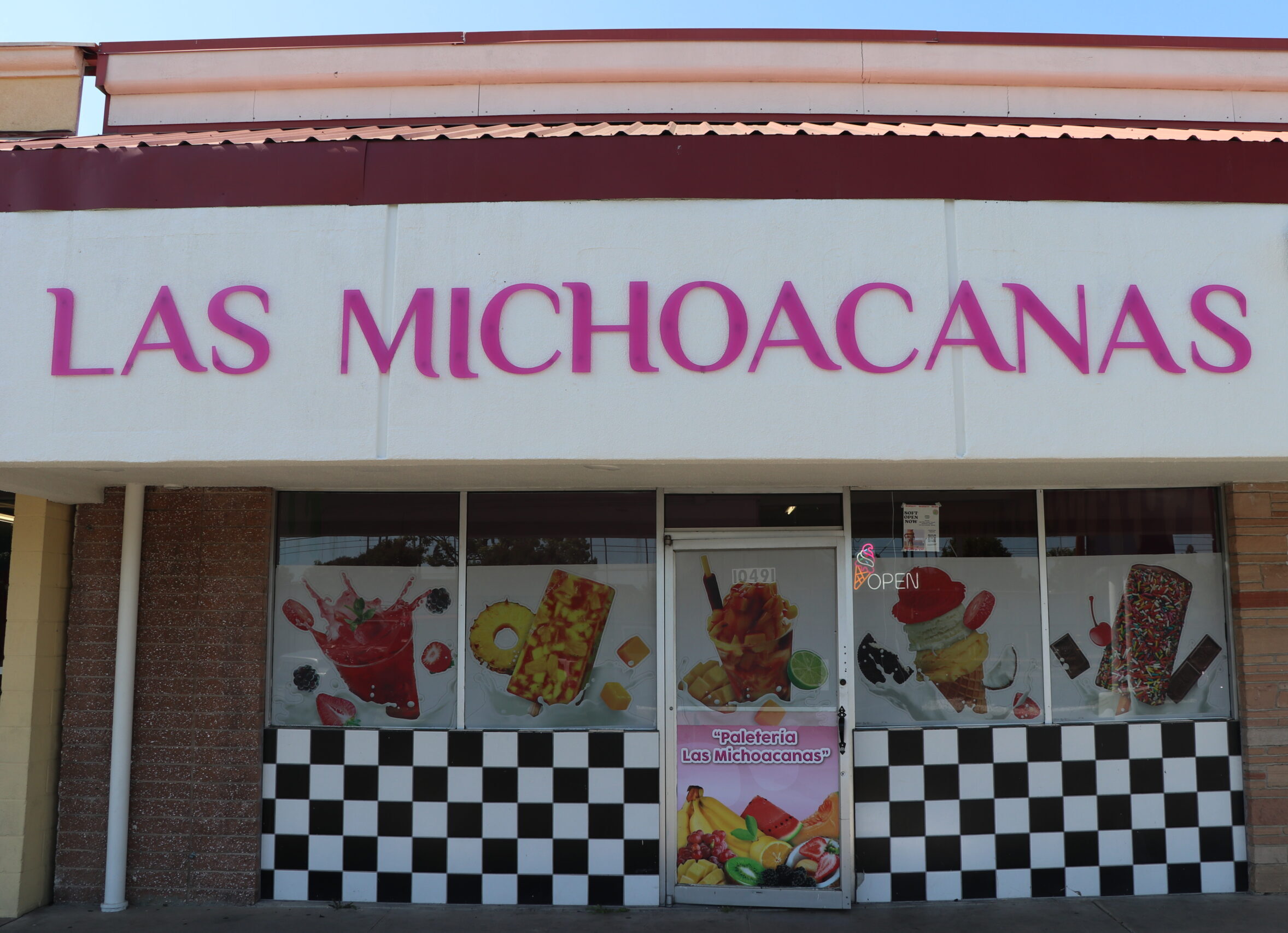 Front entrance of Las Michoacanas ice cream shop in Rancho Cordova, featuring paleta and dessert graphics on the windows with open doors welcoming guests