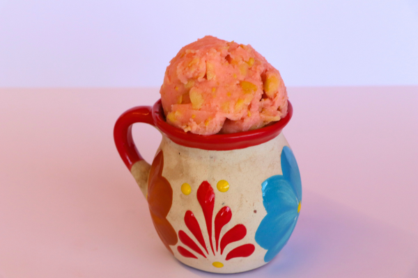 Pink guava sorbet with fruit chunks in a traditional painted clay cup